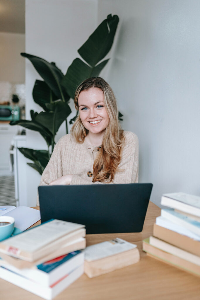 Smiling woman at her desk surrounded by study materials while studying for her social media manager qualification with Blazebridge Academy